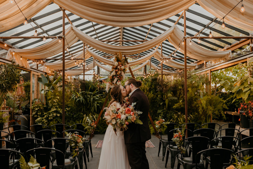 married couple kissing in the Orangerie Venue at Pomarius Greenhouse