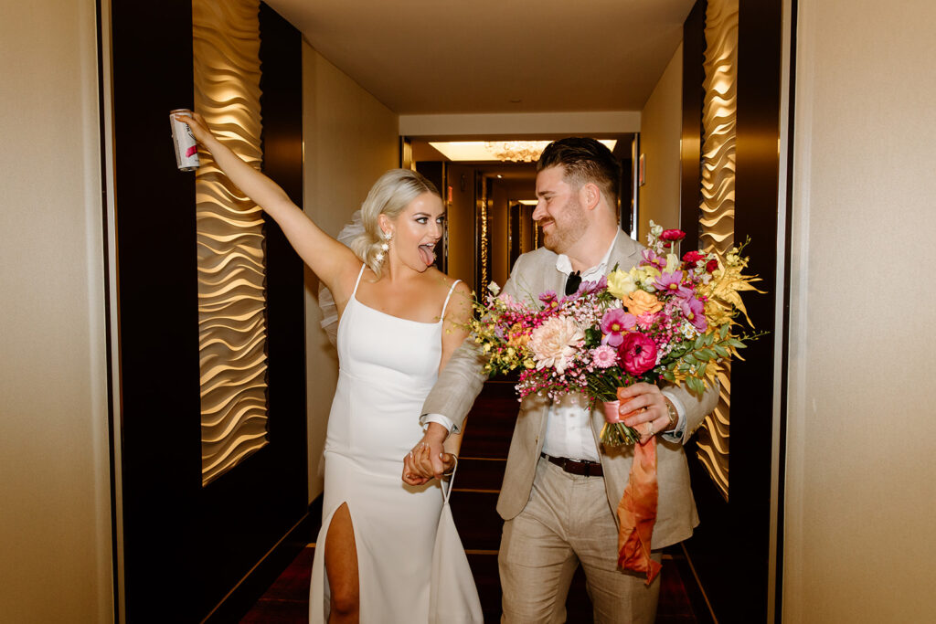couple walking through a hotel lobby in their wedding clothes